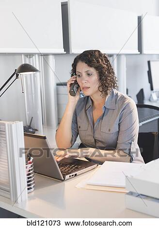 Stock Image - Hispanic businesswoman working in office. Fotosearch