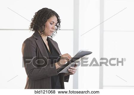 Stock Photo - Hispanic businesswoman writing in office. Fotosearch