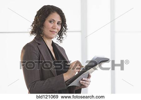 Stock Photo - Hispanic businesswoman writing in office. Fotosearch