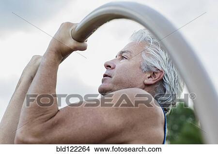 Hispanic man doing pull-ups outdoors View Large Photo Image Picture - Hispanic man doing pull-ups outdoors. Fotosearch
