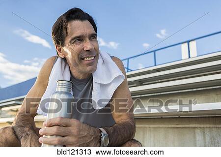 Stock Image - Hispanic man resting on bleachers. Fotosearch