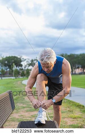 Hispanic man tying shoe in park View Large Photo Image Stock Image - Hispanic man tying shoe in park. Fotosearch