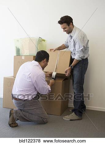 Stock Photo - Hispanic men packing cardboard boxes. Fotosearch