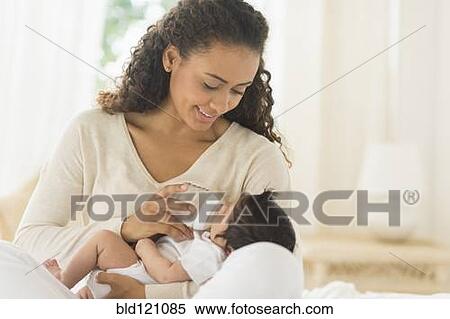 Stock Photography - Hispanic mother feeding newborn baby. Fotosearch