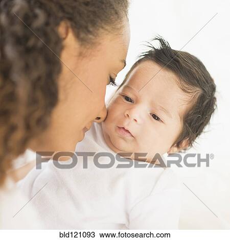Stock Image - Hispanic mother nuzzling baby's cheek. Fotosearch