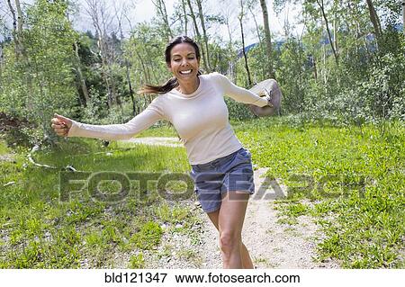 Stock Photo - Hispanic woman skipping in forest. Fotosearch