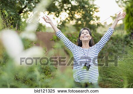 Stock Photography - Hispanic woman standing with arms outstretched outdoors. Fotosearch