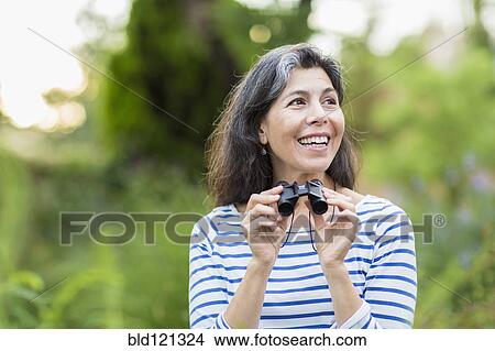Hispanic woman using binoculars outdoors View Large Photo Image Picture - Hispanic woman using binoculars outdoors. Fotosearch
