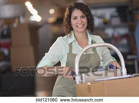 Stock Image - Hispanic woman working in warehouse. Fotosearch