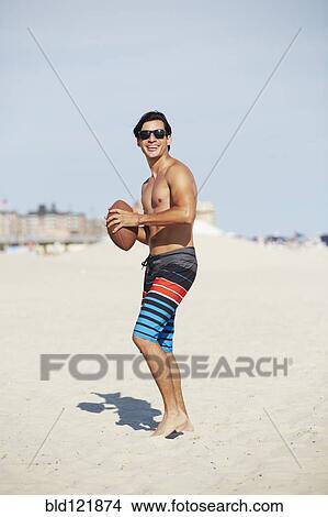Picture - Man playing with football on beach. Fotosearch