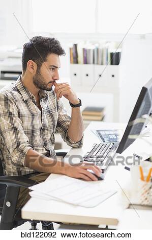 Stock Image - Mixed race businessman working in office. Fotosearch