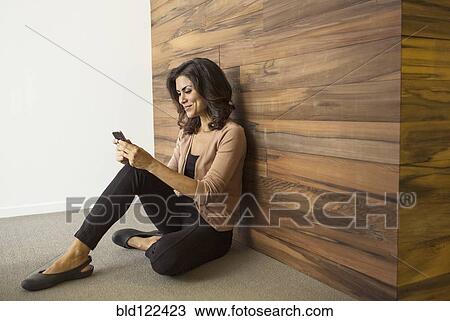 Stock Image - Mixed race businesswoman using cell phone. Fotosearch