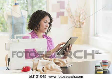 Stock Photography - Mixed race dressmaker using digital tablet. Fotosearch