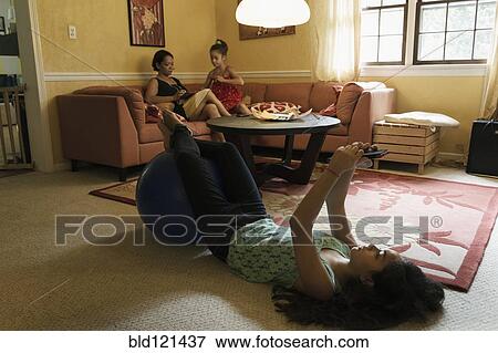 Stock Photo - Mixed race family relaxing in living room. Fotosearch