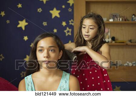 Mixed race girl brushing sister's hair View Large Photo Image Stock Photo - Mixed race girl brushing sister's hair. Fotosearch