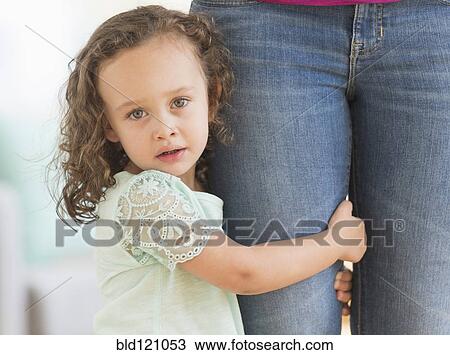 Stock Image - Mixed race girl clinging to mother's leg. Fotosearch