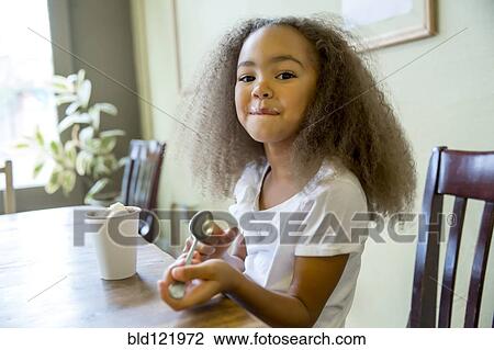 Stock Image - Mixed race girl enjoying hot chocolate. Fotosearch