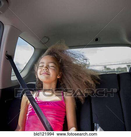 Mixed race girl enjoying wind in hair in back seat of car View Large Photo Image Picture - Mixed race girl enjoying wind in hair in back seat of car. Fotosearch
