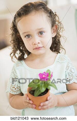 Stock Image - Mixed race girl holding flowerpot. Fotosearch