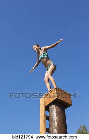 Picture - Mixed race girl jumping off platform. Fotosearch