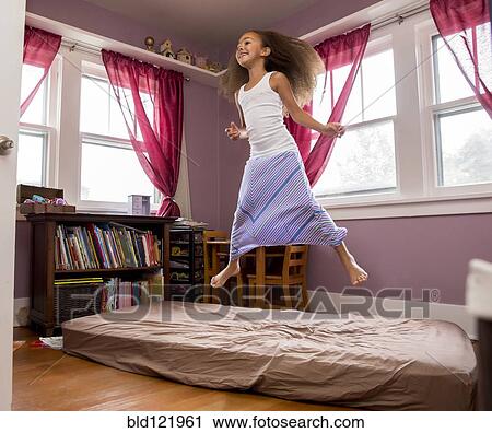 Mixed race girl jumping on bed View Large Photo Image Stock Image - Mixed race girl jumping on bed. Fotosearch