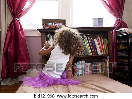 Stock Photo - Mixed race girl picking books from shelf. Fotosearch