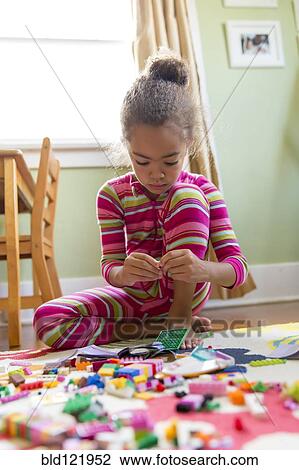 Stock Image - Mixed race girl playing in kitchen. Fotosearch