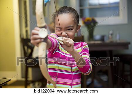 Picture - Mixed race girl playing with bow and arrow. Fotosearch