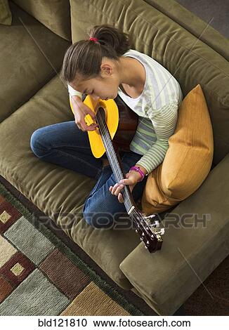 Mixed race girl practicing guitar on sofa View Large Photo Image Stock Image - Mixed race girl practicing guitar on sofa. Fotosearch