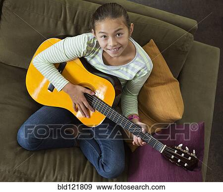 Mixed race girl practicing guitar on sofa View Large Photo Image Stock Photo - Mixed race girl practicing guitar on sofa. Fotosearch