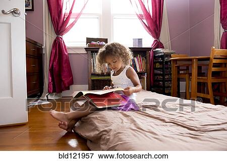 Stock Photo - Mixed race girl reading in bedroom. Fotosearch