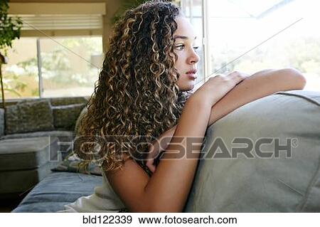 Mixed race girl sitting on sofa View Large Photo Image Stock Photo - Mixed race girl sitting on sofa. Fotosearch