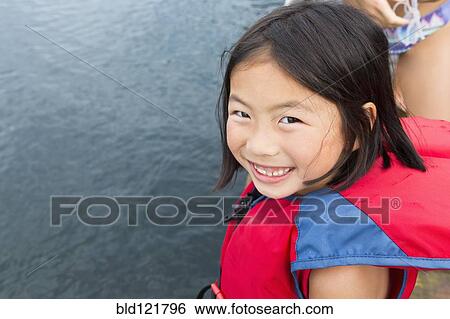 Stock Photograph - Mixed race girl smiling by lake. Fotosearch