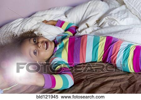 Stock Photography - Mixed race girl smiling on bed. Fotosearch