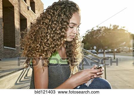 Stock Image - Mixed race girl using cell phone. Fotosearch