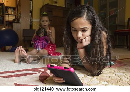 Stock Image - Mixed race girl using digital tablet on floor. Fotosearch