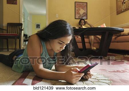 Stock Photo - Mixed race girl using digital tablet on floor. Fotosearch