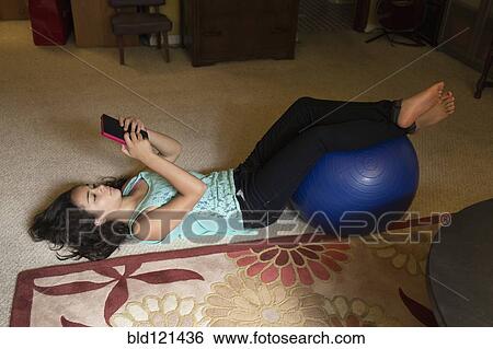 Stock Photograph - Mixed race girl using digital tablet on floor. Fotosearch