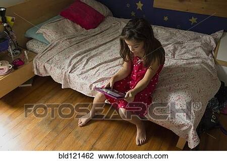 Stock Image - Mixed race girl using digital tablet. Fotosearch