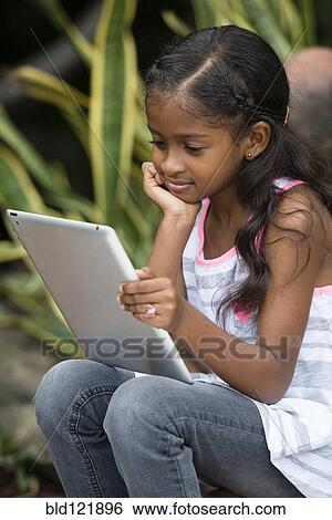 Mixed race girl using digital tablet outdoors View Large Photo Image Stock Photograph - Mixed race girl using digital tablet outdoors. Fotosearch