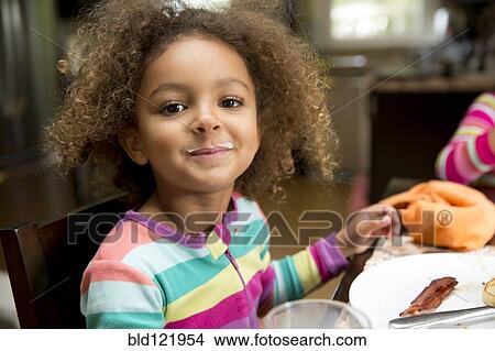 Picture - Mixed race girl with milk mustache at table. Fotosearch