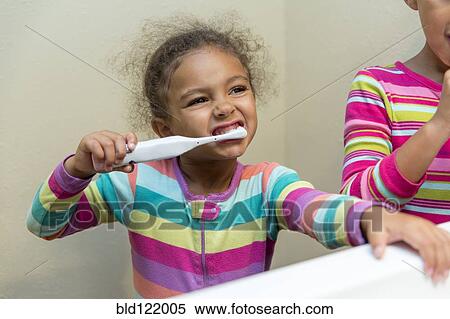 Stock Photography - Mixed race girls brushing their teeth. Fotosearch