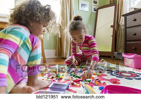 Stock Image - Mixed race girls playing in bedroom. Fotosearch