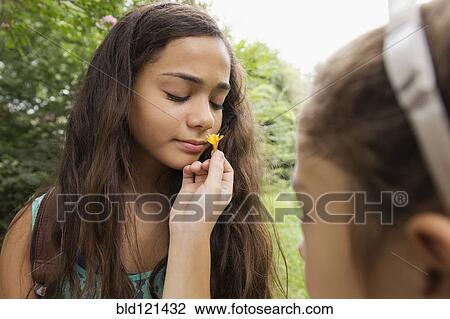 Stock Image - Mixed race girls smelling flowers. Fotosearch