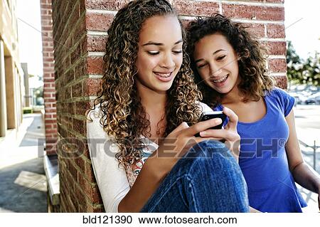 Mixed race girls using cell phone outdoors View Large Photo Image Stock Image - Mixed race girls using cell phone outdoors. Fotosearch