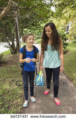 Stock Image - Mixed race girls walking to school. Fotosearch