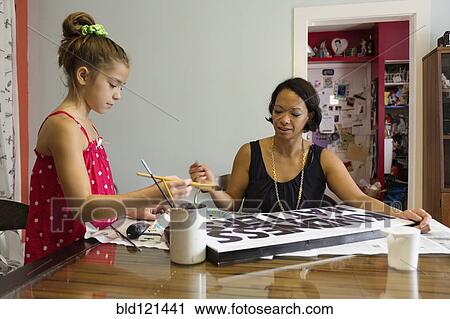 Stock Image - Mixed race mother and daughter painting sign. Fotosearch