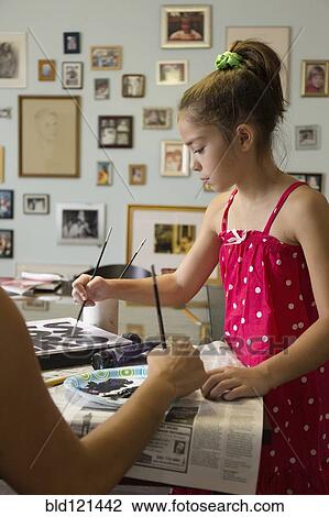 Stock Image - Mixed race mother and daughter painting sign. Fotosearch
