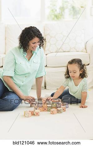 Stock Photograph - Mixed race mother and daughter playing with wooden blocks. Fotosearch