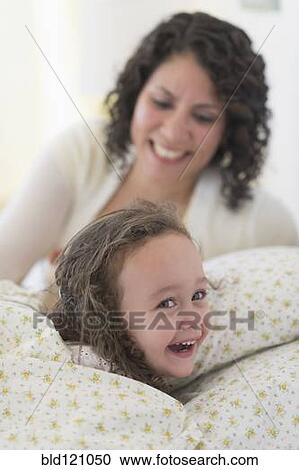 Mixed race mother putting daughter to bed View Large Photo Image Stock Image - Mixed race mother putting daughter to bed. Fotosearch